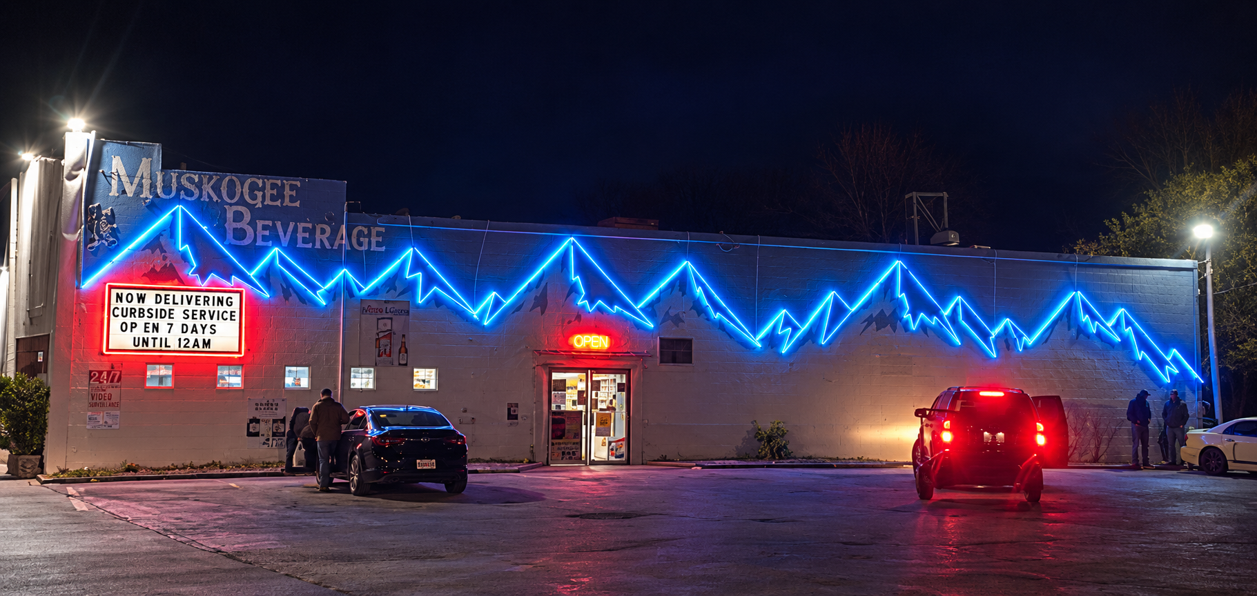Blue zigzag neon lighting across the Muskogee Beverage storefront at night